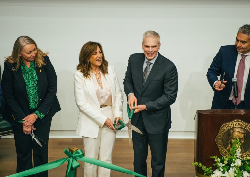 President Brad D. Smith and First Lady Alys Smith holding oversized scissors together at a ribbon cutting.