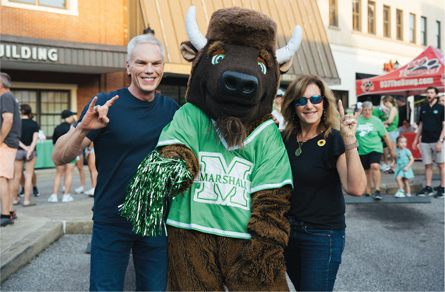 brad d. smith and alys smith standing with marco the bison in a marshall university jersey